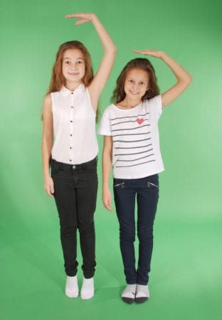 School girls hold hands above head and measuring their growth after tall stature treatment by Dr. Joshua Smith, a pediatric endocrinologist in Pocatello and Idaho Falls.